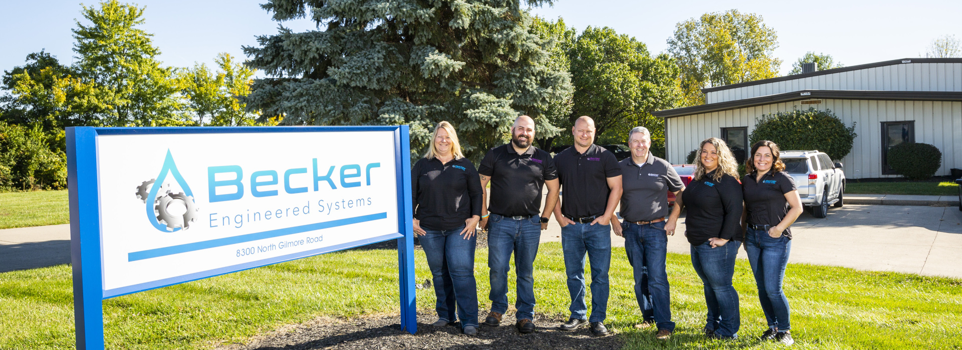 Becker staff standing outside next to the company sign